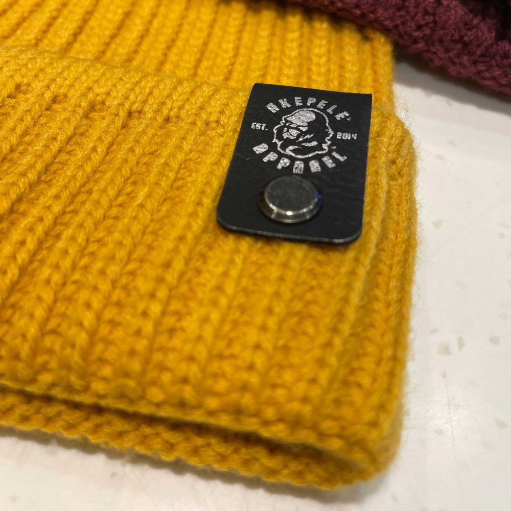 Akepele ribbed knit beanie faux leather patch, close up.